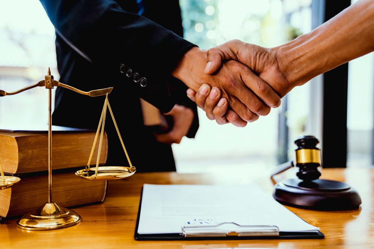 Male lawyer with client shaking hands in office.jpg